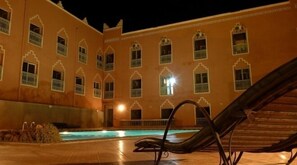 Une cour avec une piscine et des chaises longues.