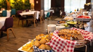 Een buffetopstelling met diverse soorten eten en een geruit kleedje over het brood.