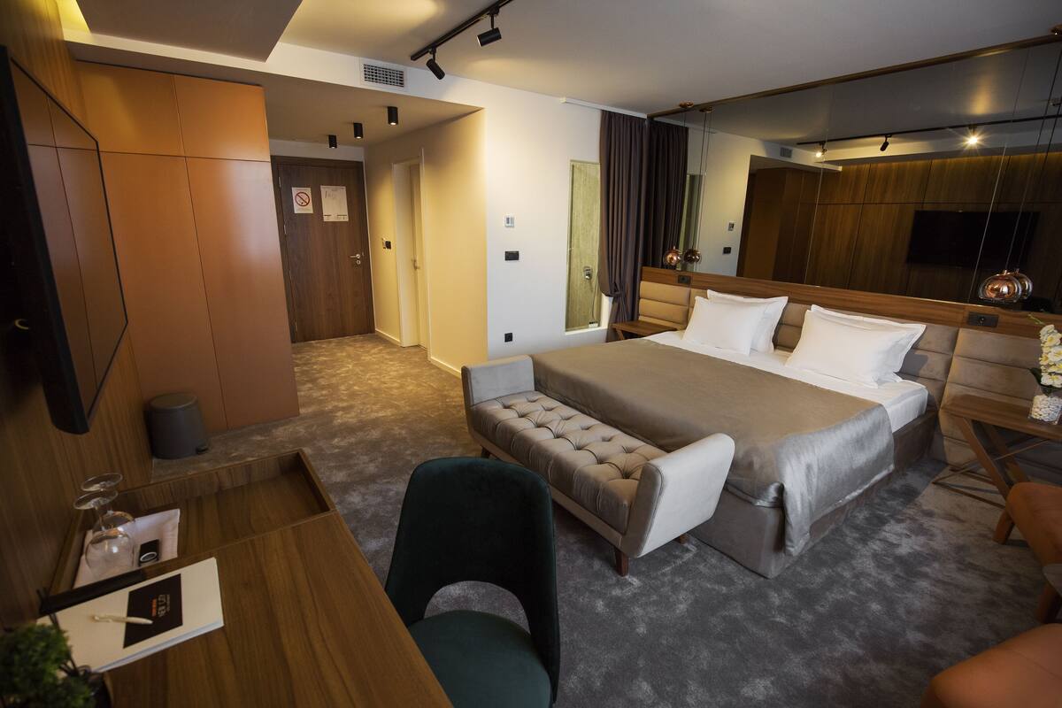 Ein modernes Hotelzimmer mit einem großen Bett, einem Schreibtisch, einem Stuhl und einer kleinen Sitzecke.