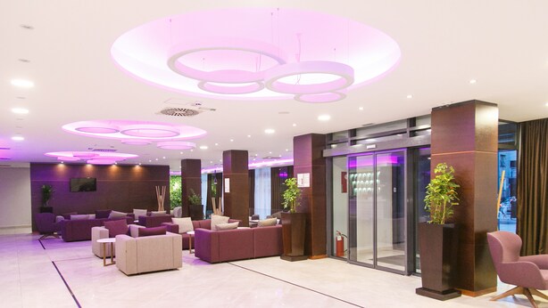 Een moderne lobby met zithoeken, een receptiebalie en een glazen entree.