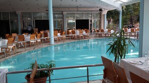 An indoor swimming pool with tables and chairs arranged around it. - Arsan Otel (Kahramanmaras)