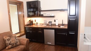 A compact kitchen with dark cabinetry, a dishwasher, a microwave, and a coffee maker. - The Fields of Eden Inn (Eden)