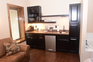 Una cocina compacta con muebles oscuros, lavavajillas, microondas y cafetera.