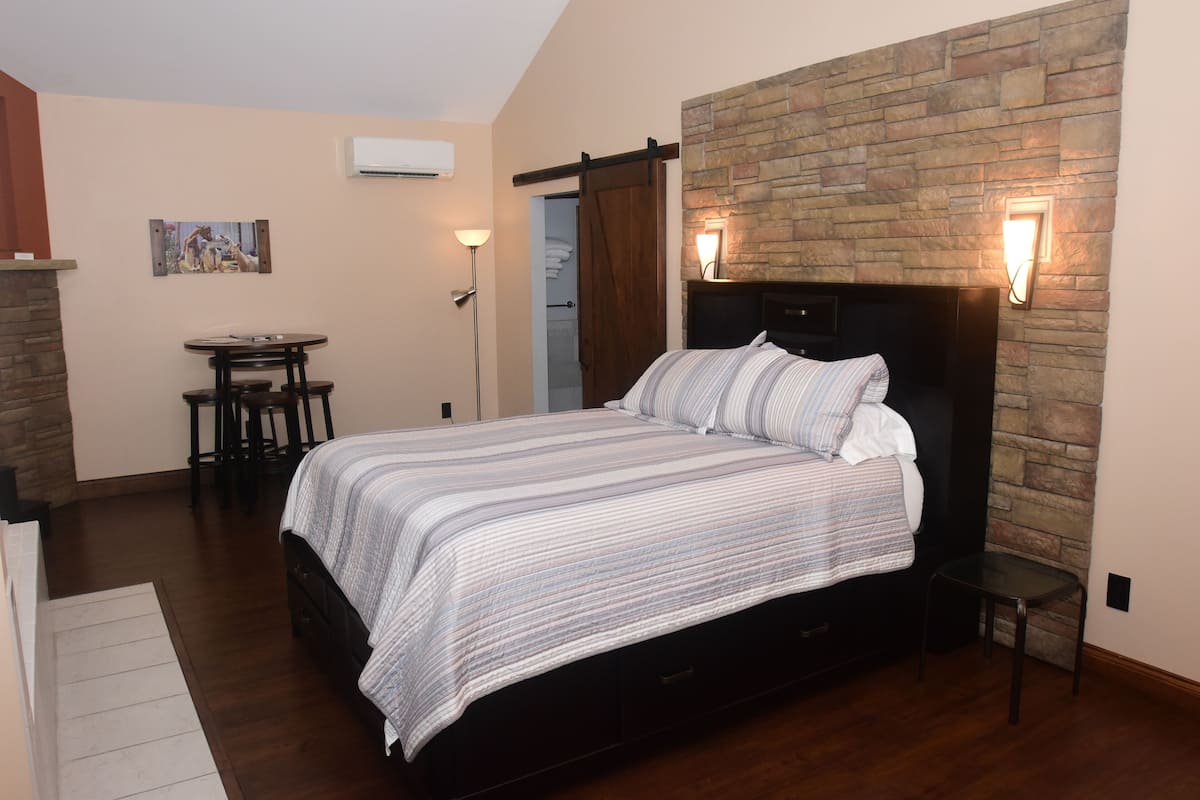 A bedroom with a bed, a small table, and a chair.