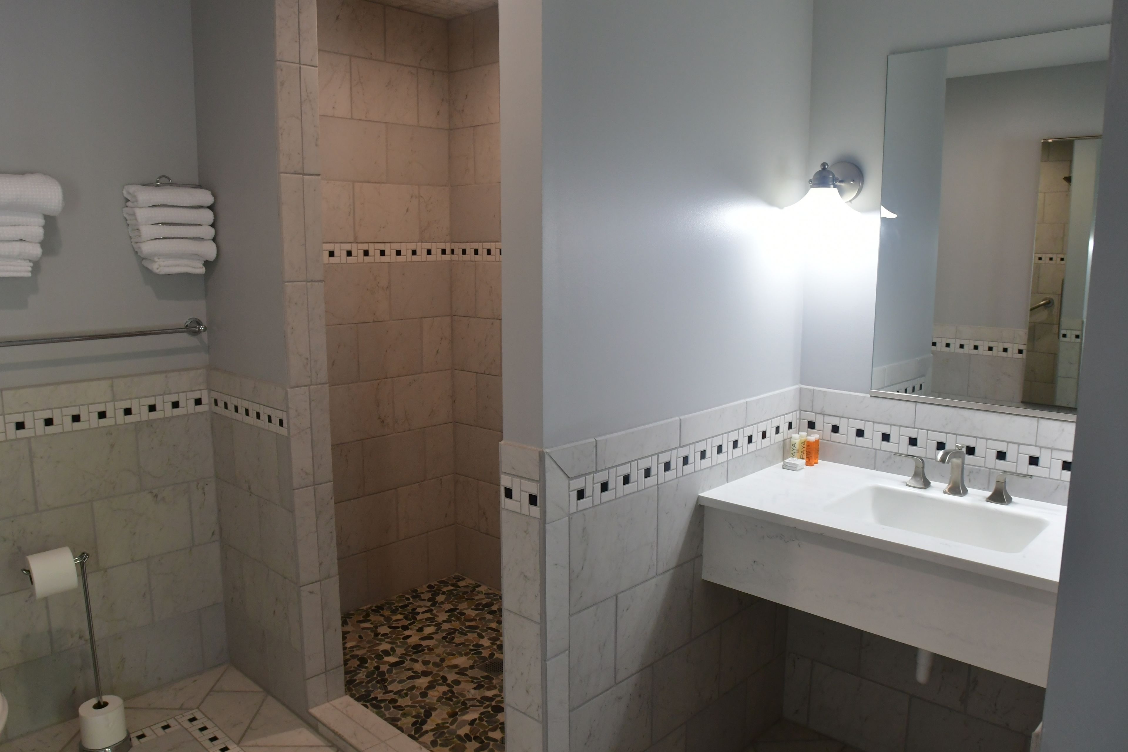 A bathroom with a shower, a sink with a mirror, and a toilet.