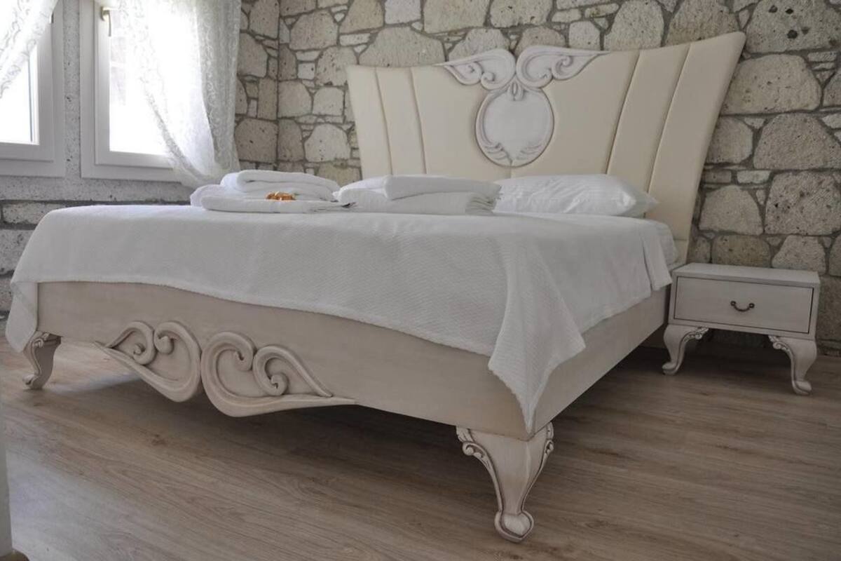 A bed with a white headboard and footboard, a bedside table, and a nightstand.