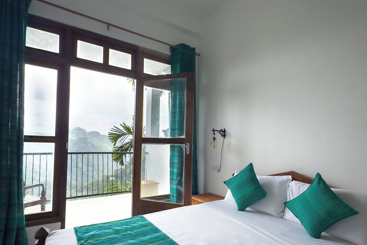 A bedroom with a bed, a view of the outdoors, and a ceiling fan.