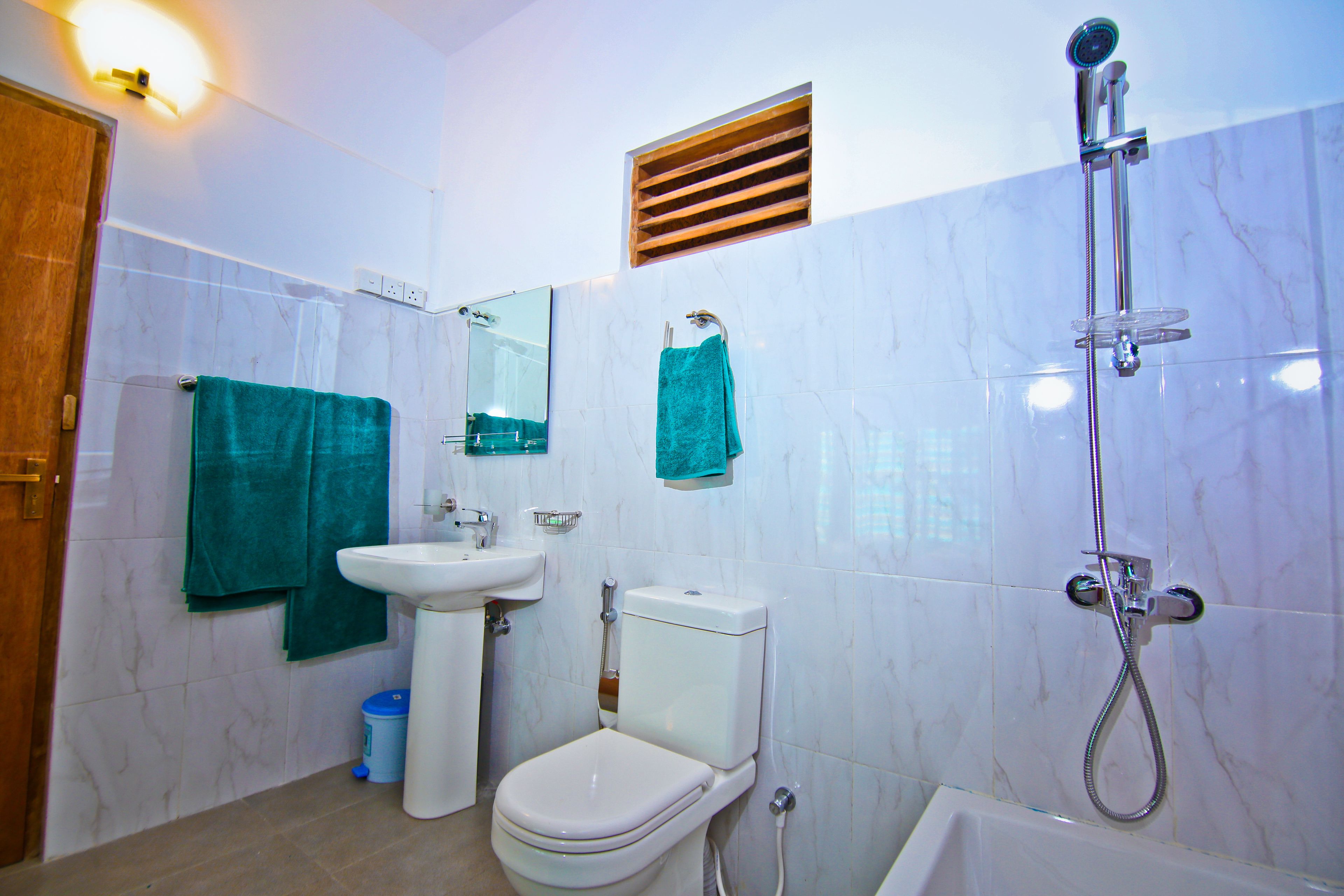 A bathroom with a toilet, sink, mirror, and shower.