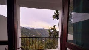 A balcony with a view of a mountainous landscape and a palm tree. - Ella Alpine Resort (Ella)