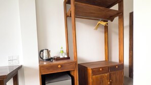A compact wooden desk with a built-in mini-fridge, a kettle, and a water bottle. - Ella Alpine Resort (Ella)