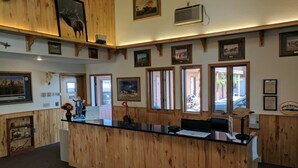 A reception area with wooden paneling, framed artwork, and a counter with a black surface. - Travelodge by Wyndham Three Forks (Three Forks)