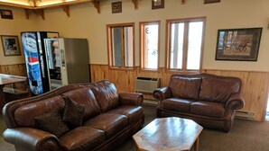 A living room with two brown leather sofas, a wooden coffee table, and a large refrigerator with a Pepsi logo. - Travelodge by Wyndham Three Forks (Three Forks)
