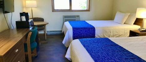 Une chambre d’hôtel avec deux lits, un bureau, une chaise, une télévision et une fenêtre avec des rideaux.