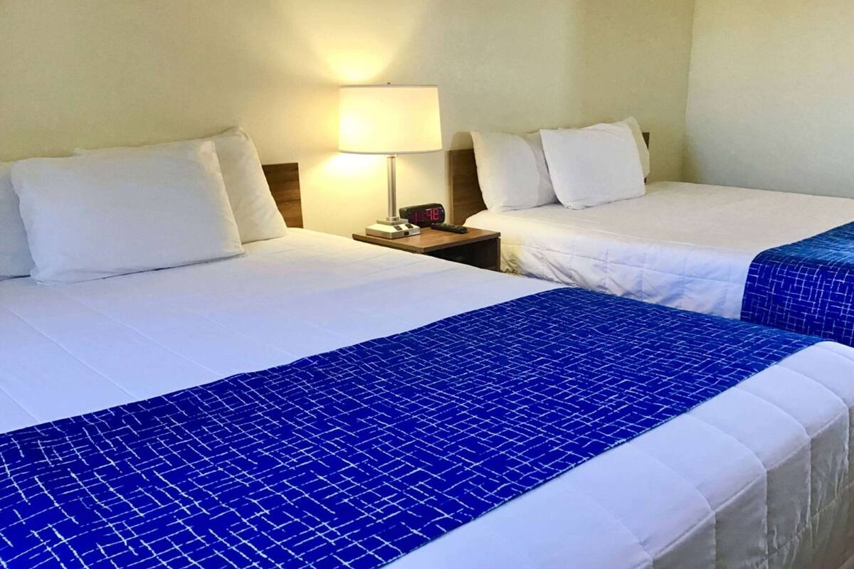 Two beds with white linens and blue patterned bedspreads in a hotel room.