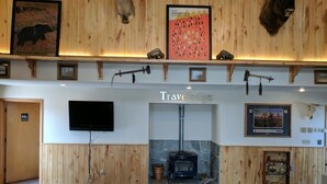 A lobby with wooden paneling, a fireplace, mounted animal heads, and a television. - Travelodge by Wyndham Three Forks (Three Forks)