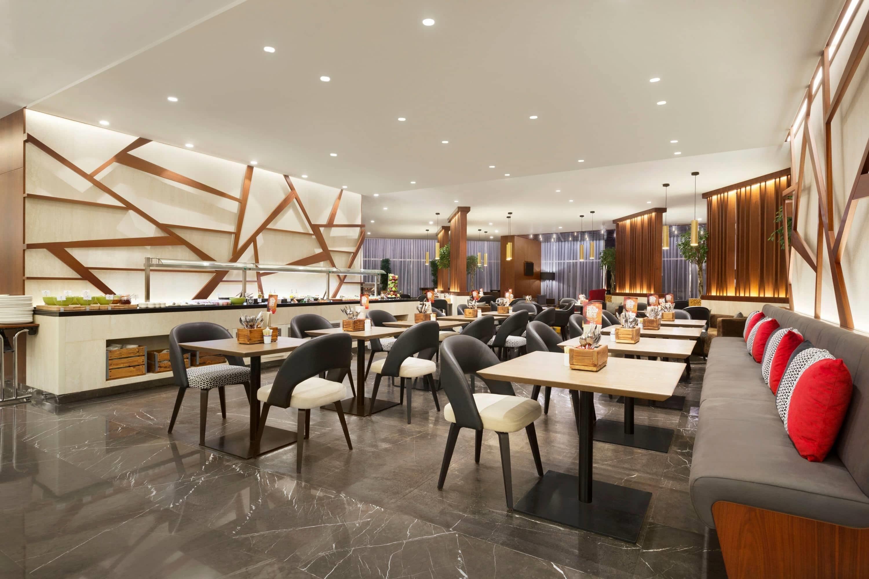 Un espace repas moderne comprenant plusieurs tables et chaises, un comptoir central et un coin salon avec un canapé.