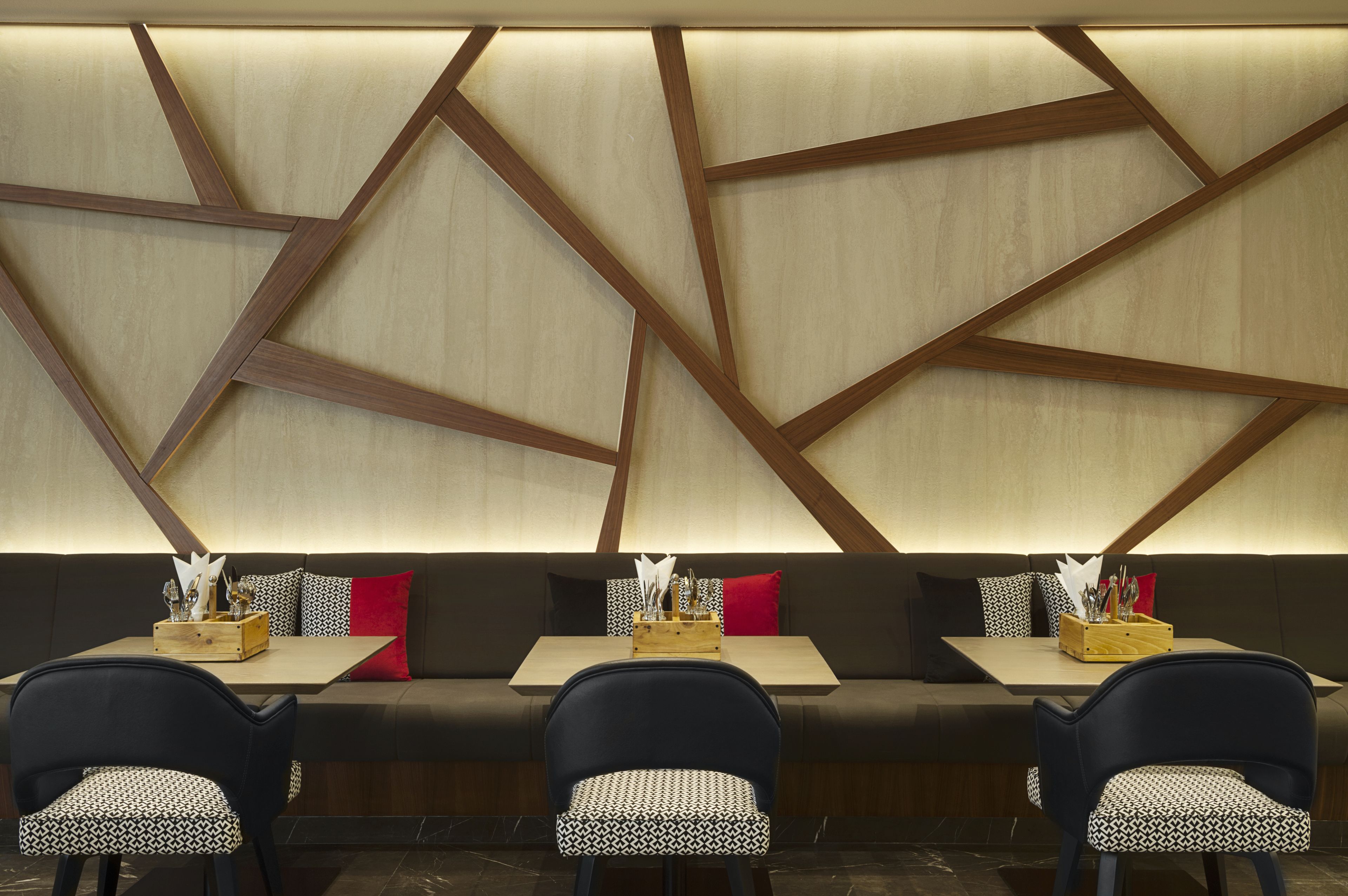 A modern restaurant interior with a long bench seating area, wooden accents, and a simple table setup.