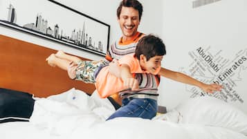 A bed with a city skyline poster and a map of Abu Dhabi on the wall.