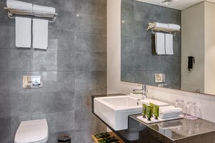 Un baño moderno con un lavamanos grande, espejo y toalleros.