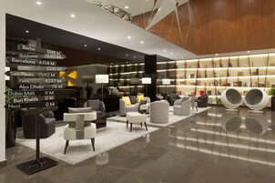 Un intérieur moderne comprenant un coin salon, une bibliothèque et des panneaux indicateurs indiquant les distances vers différentes villes.