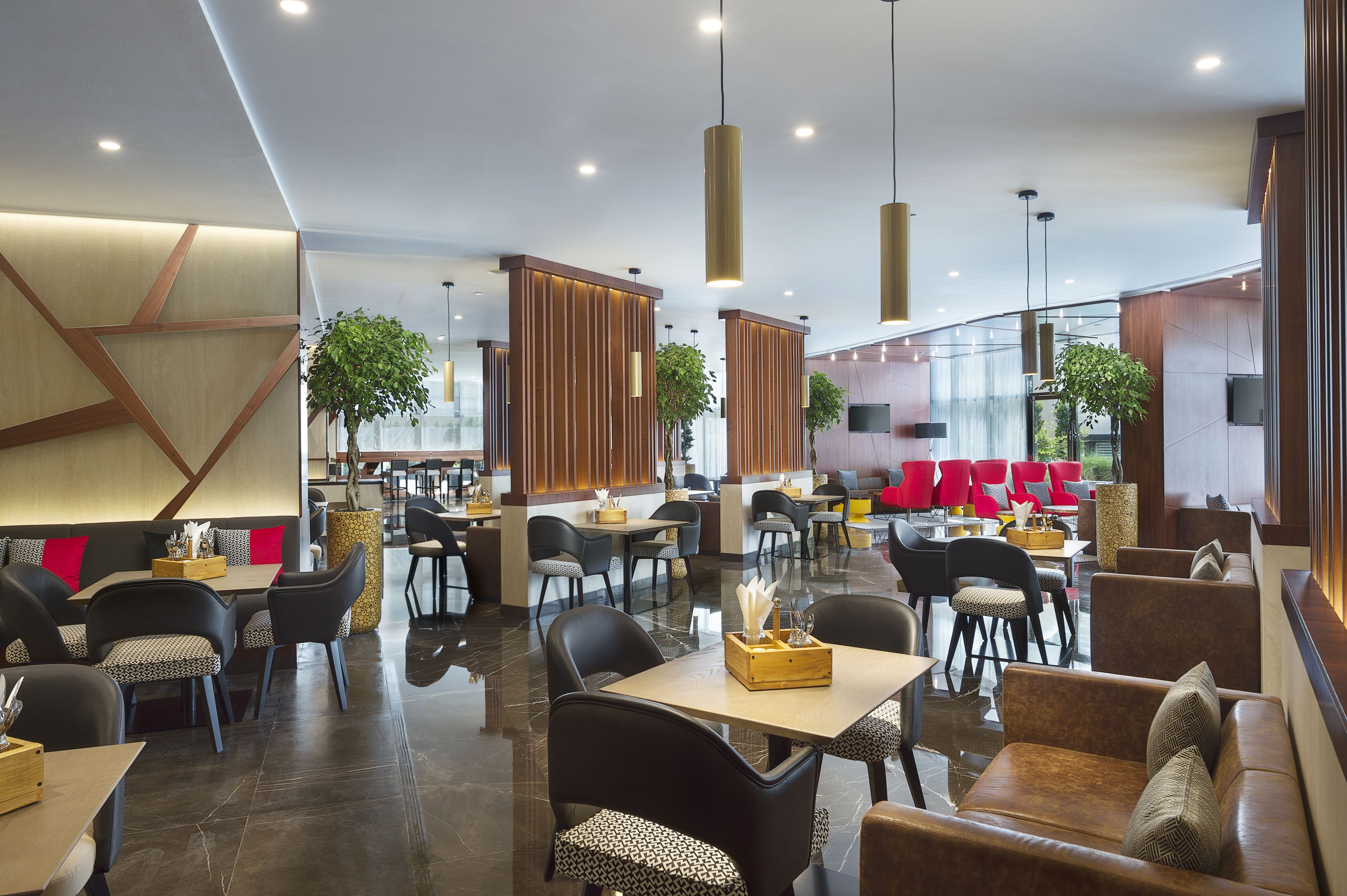 Ein modernes Restaurant mit verschiedenen Sitzgelegenheiten, darunter Boxsitzmöglichkeiten und Tische, Holzdetails und Pendelleuchten.