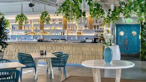 A bar area with a tiled backsplash, hanging plants, and a blue door. - TRYP by Wyndham Dubai (Dubai)