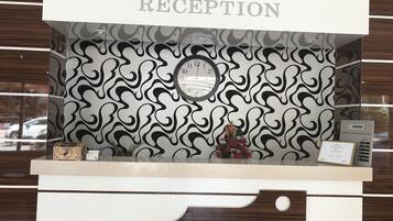 A reception desk with a 'RECEPTION' sign, a clock, and a 'FOREIGN EXCHANGE RATES' sign.