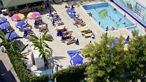 A pool area with sun loungers and umbrellas, surrounded by greenery. - Narcis Apart Hotel (Alanya)