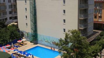 Un hotel con piscina, varios balcones y un mural en la fachada.
