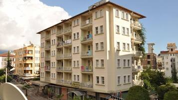 Un edificio residencial de varios pisos con balcones, una antena parabólica y vista a la calle.