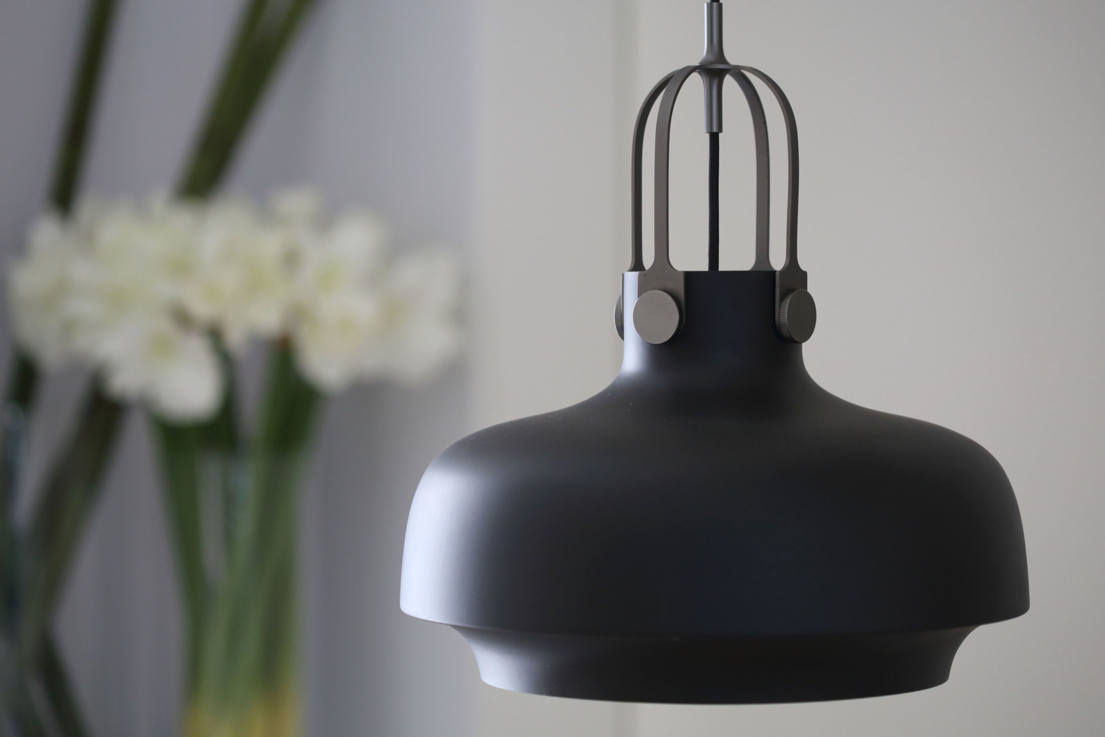 A black pendant light fixture with a unique design, hanging from a ceiling.