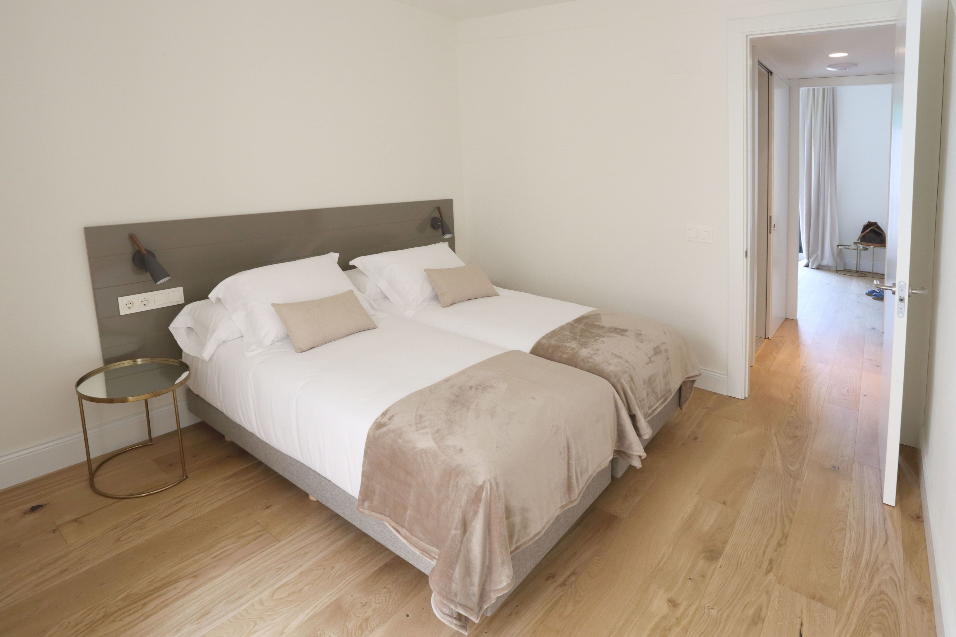 Una cama doble con cabecera de madera, una mesita de noche y un edredón beige.