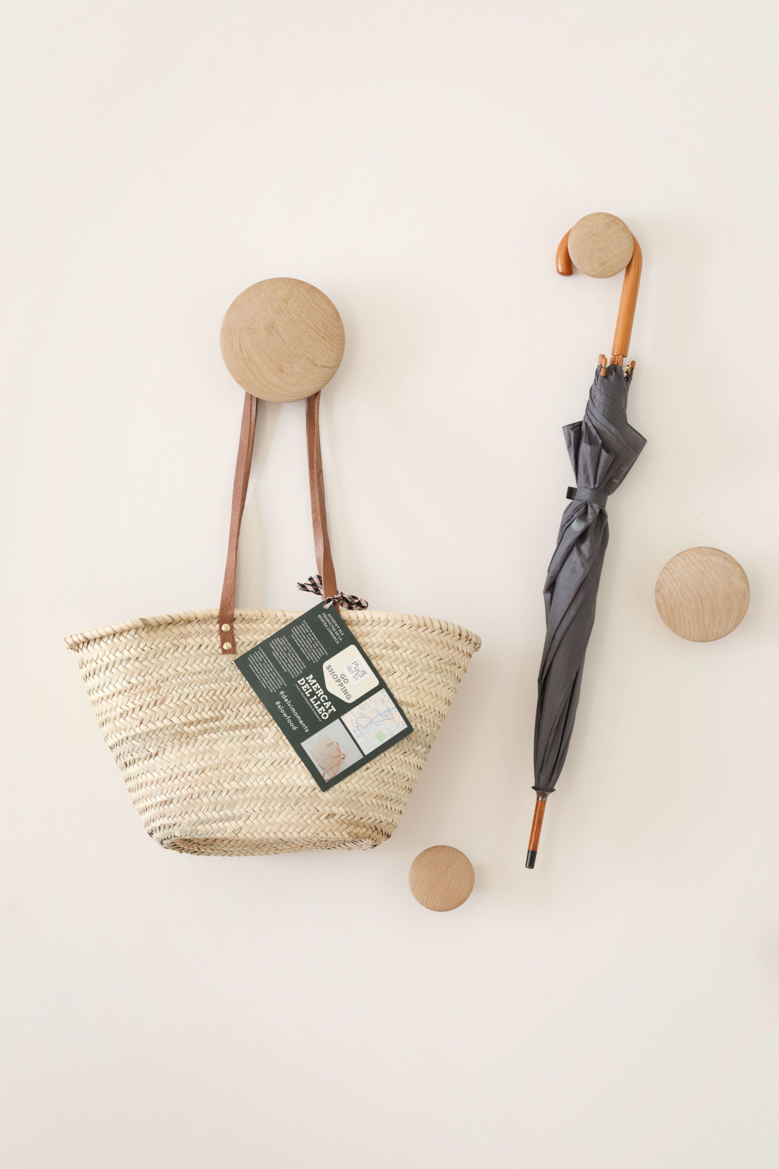 Una bolsa de tela tejida con una etiqueta y un paraguas negro con mango de madera.