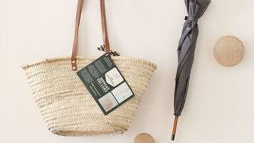 Una bolsa de tela tejida con una etiqueta y un paraguas negro con mango de madera.