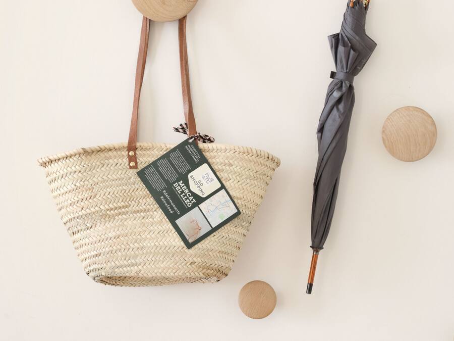 Una bolsa de tela tejida con una etiqueta y un paraguas negro con mango de madera.