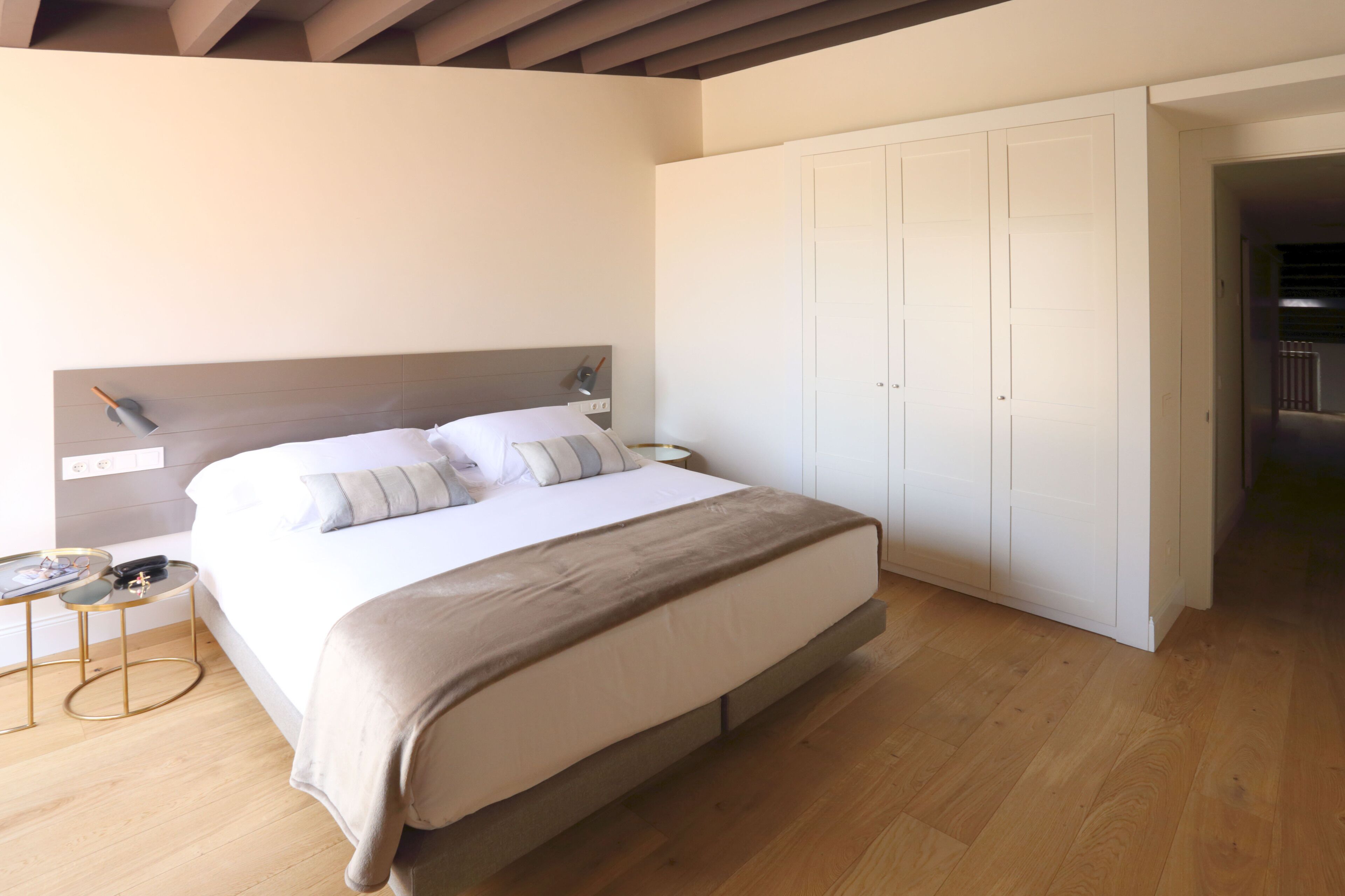 A bedroom with a bed, bedside tables, a wardrobe, and a wooden floor.