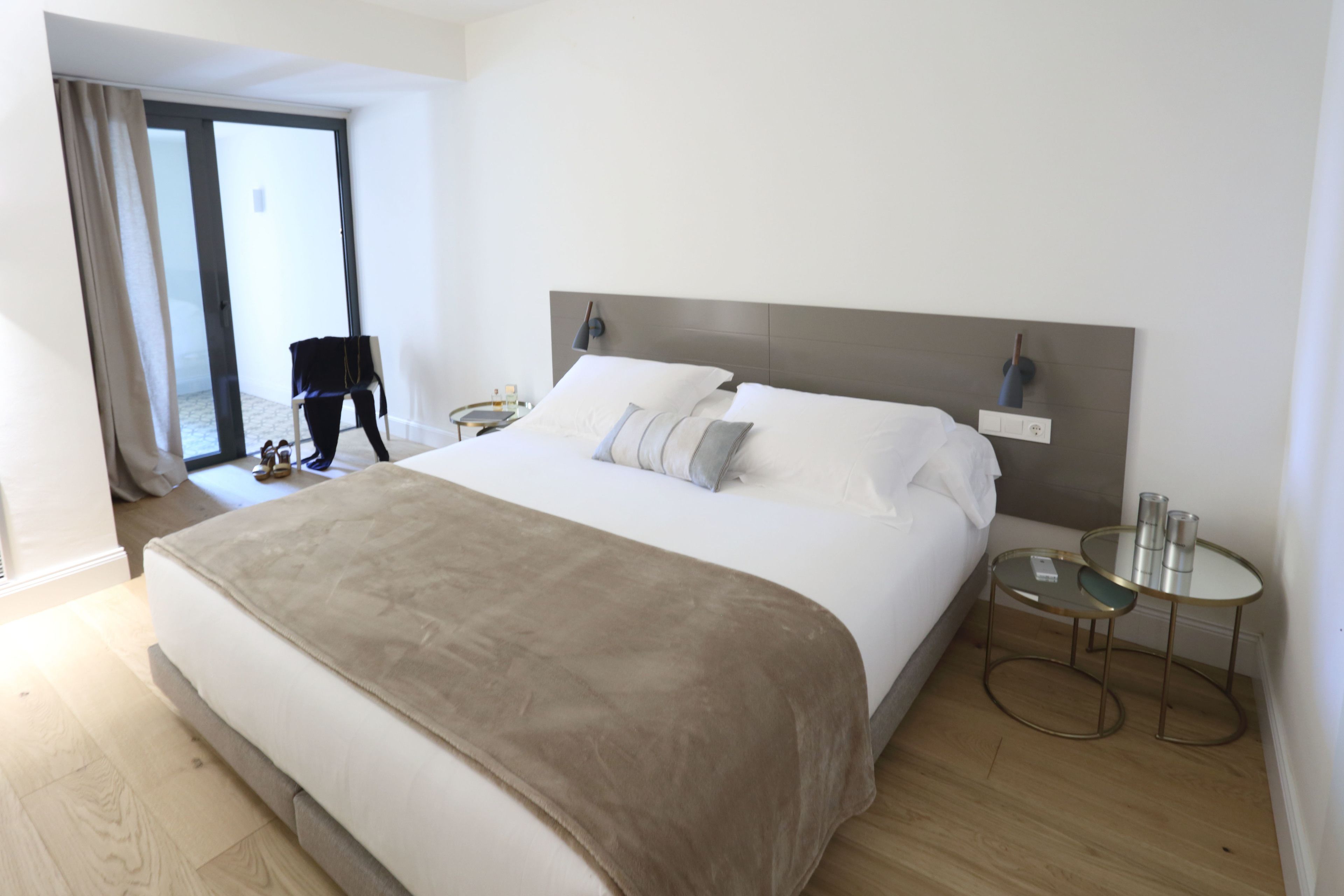 Habitación de hotel moderna con una cama grande, una mesa de vidrio y vistas al exterior.