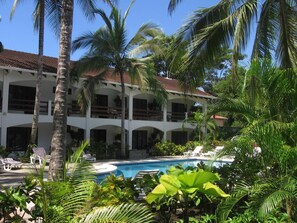 A resort with a pool, palm trees, and a two-story building with balconies.