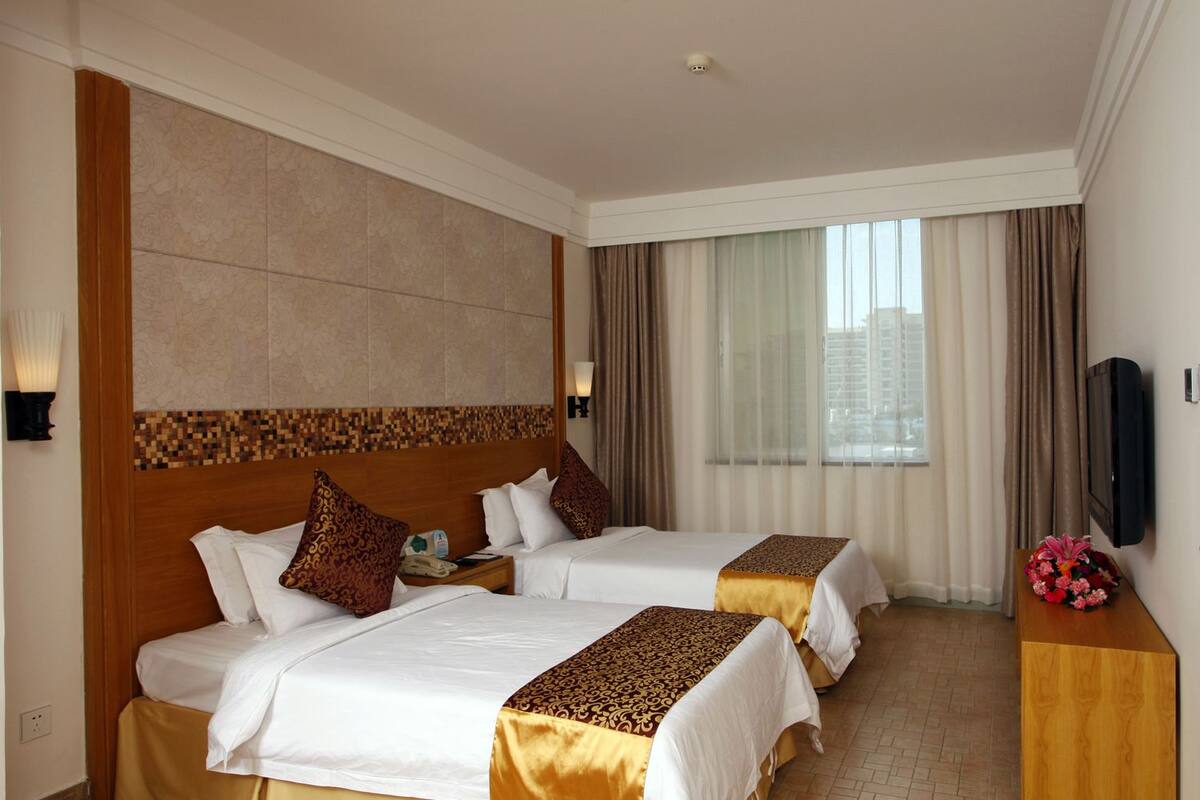 A hotel room with two beds, a TV, and a view of the city.