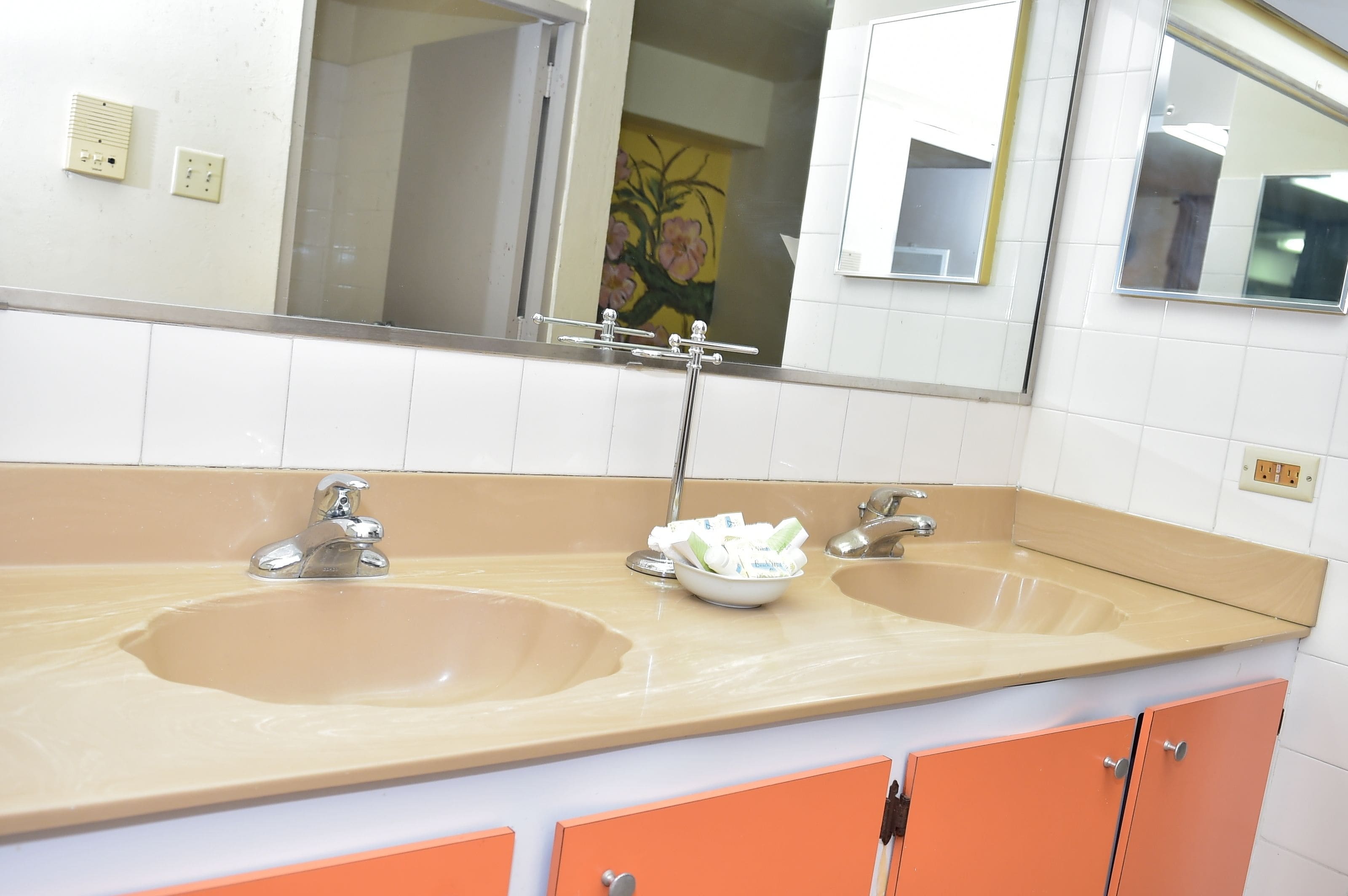 A bathroom with two sinks, a mirror, and orange cabinets.