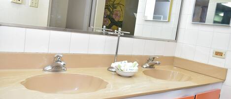 Une salle de bain avec deux lavabos, un miroir et des meubles de rangement orange.