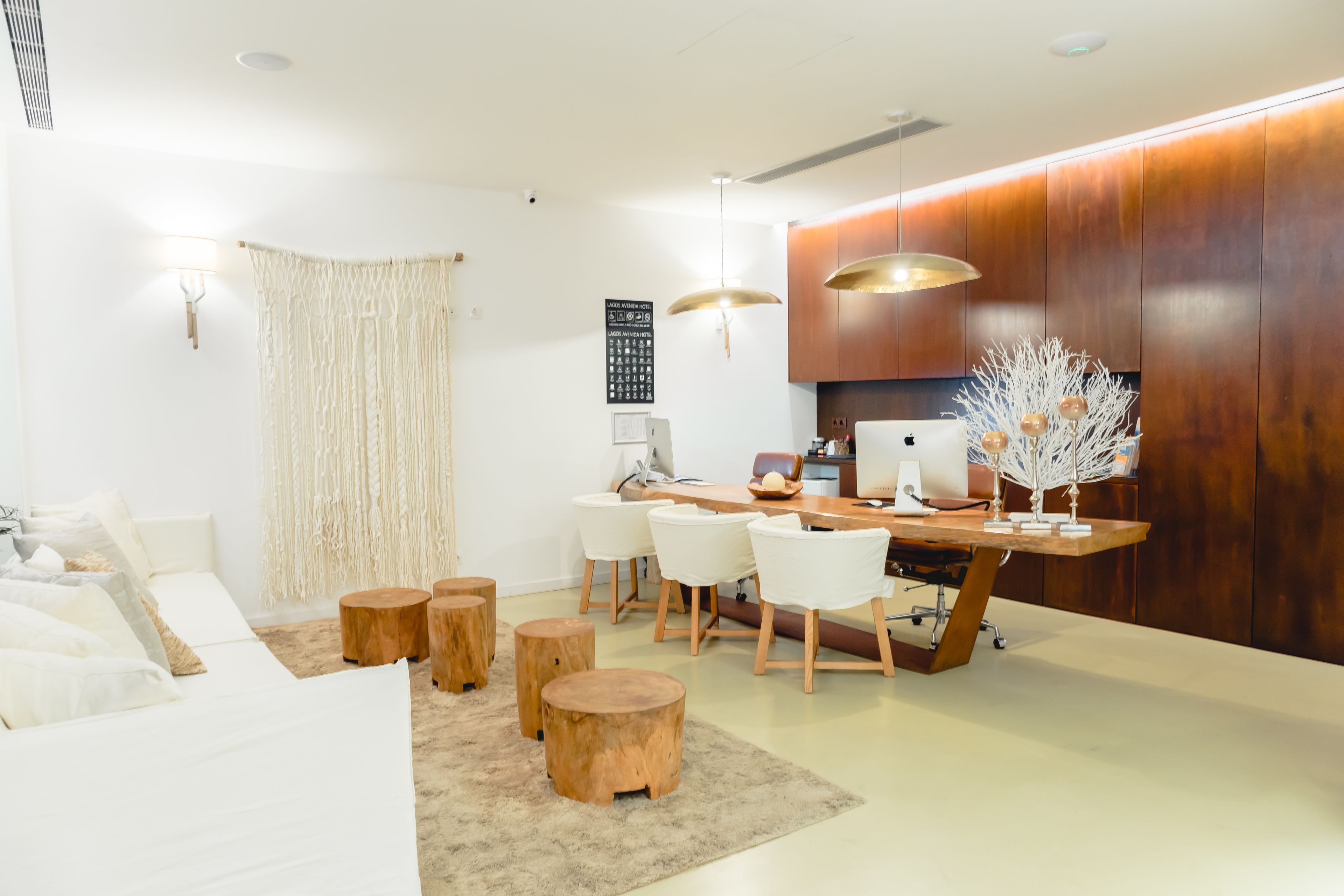 A modern living room with a sofa, wooden stools, a dining table with chairs, and a decorative tree.