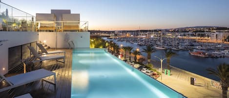 Una piscina al aire libre, sombrillas, sillones reclinables de piscina