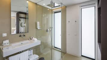 Un baño moderno con cabina de ducha de vidrio, un espejo grande y un lavabo blanco.
