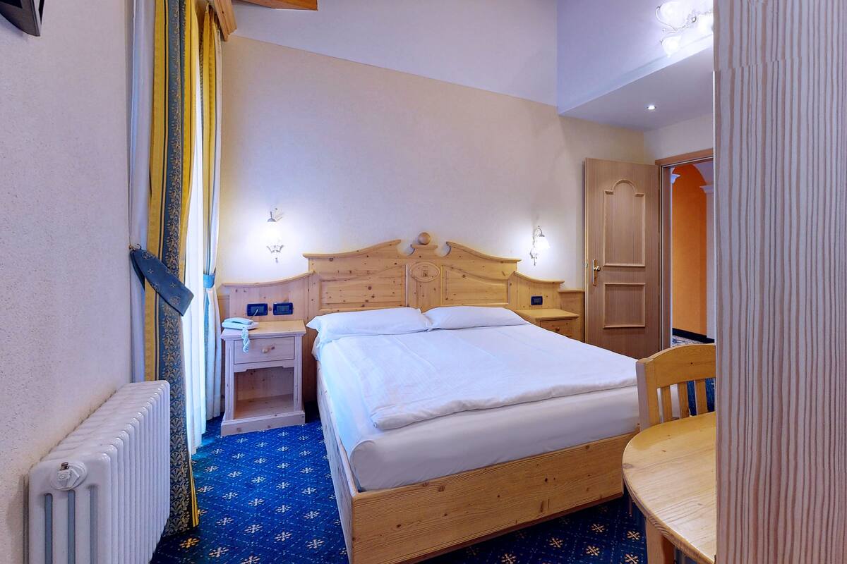 Une chambre à coucher avec un lit en bois, des tables de chevet, un radiateur et une porte en bois.