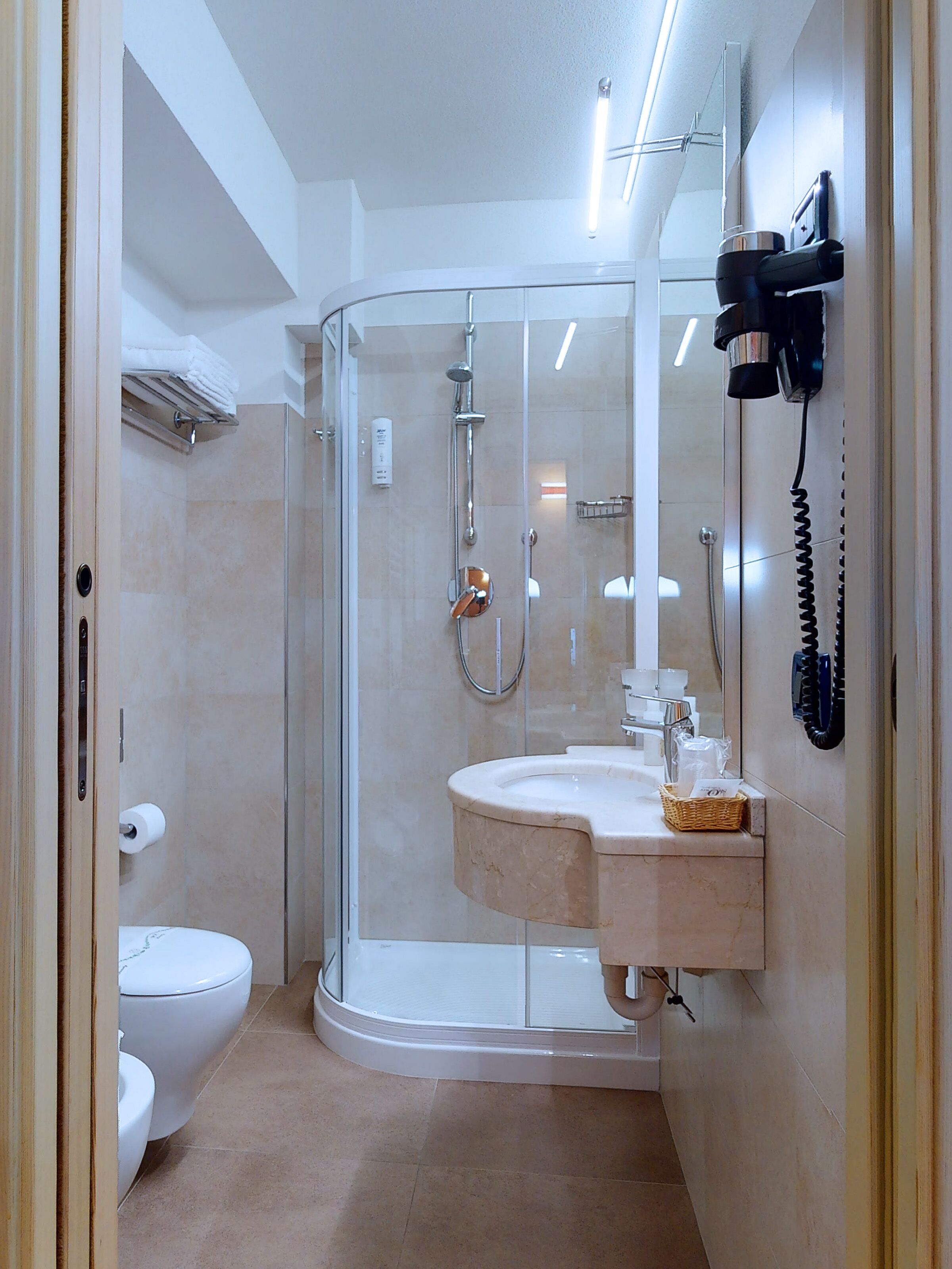 A modern bathroom with a glass-enclosed shower, a white toilet, and a sink with a marble countertop.
