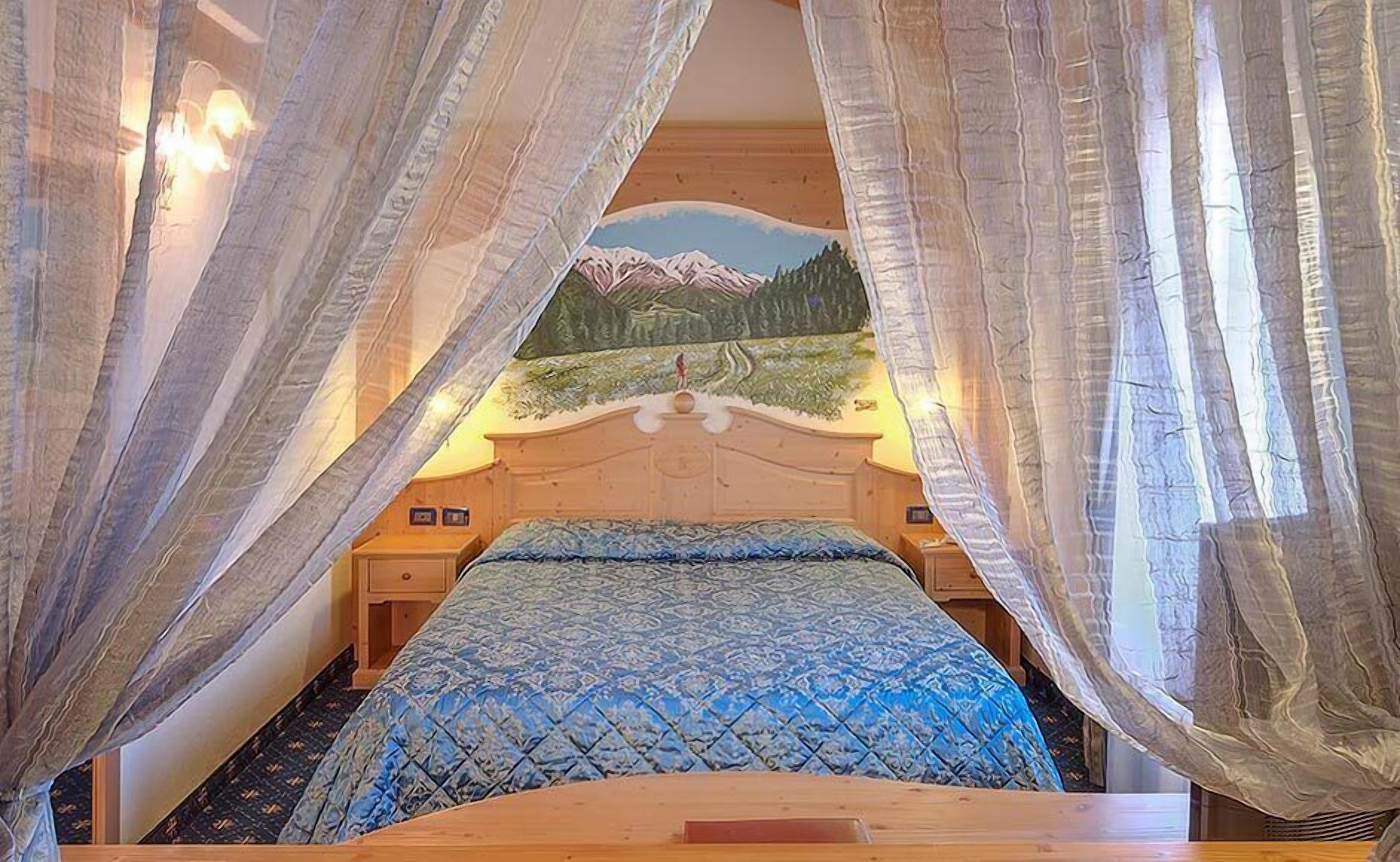 A bedroom with a bed, a nightstand, and a wall-mounted lamp.