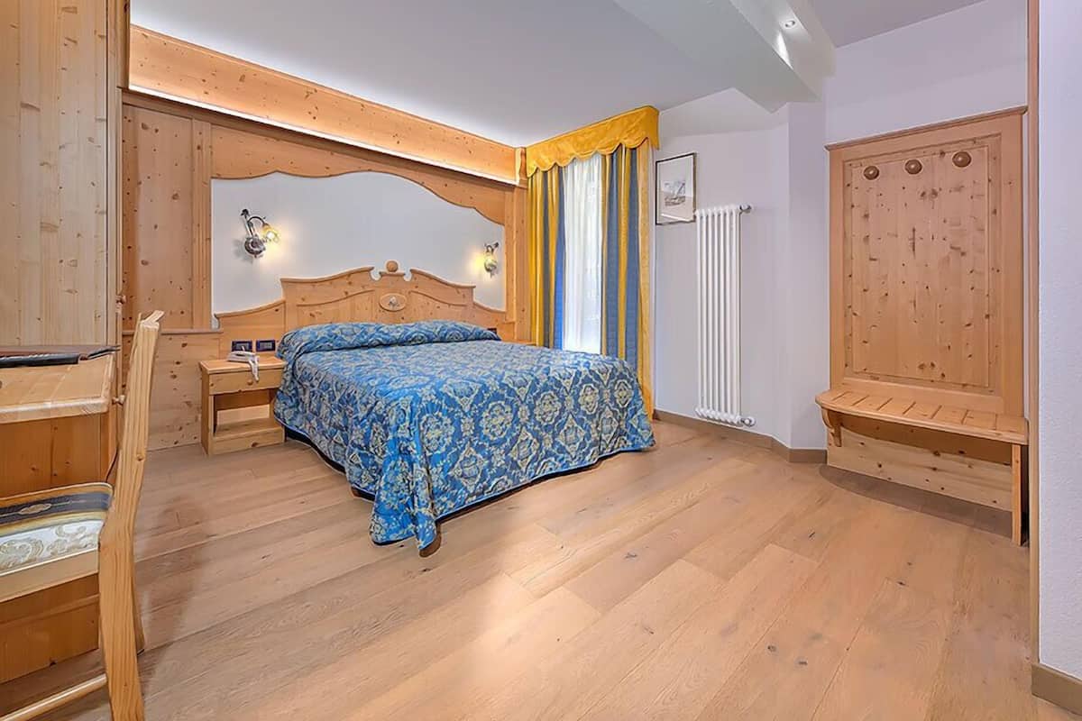 Une chambre à coucher avec un lit en bois, une table de chevet, une chaise et une armoire.