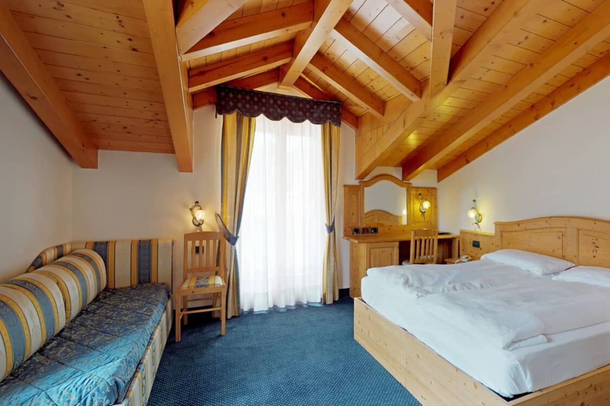 Une chambre à coucher avec un cadre en bois, comprenant un lit, un canapé, une chaise et un bureau avec un miroir.