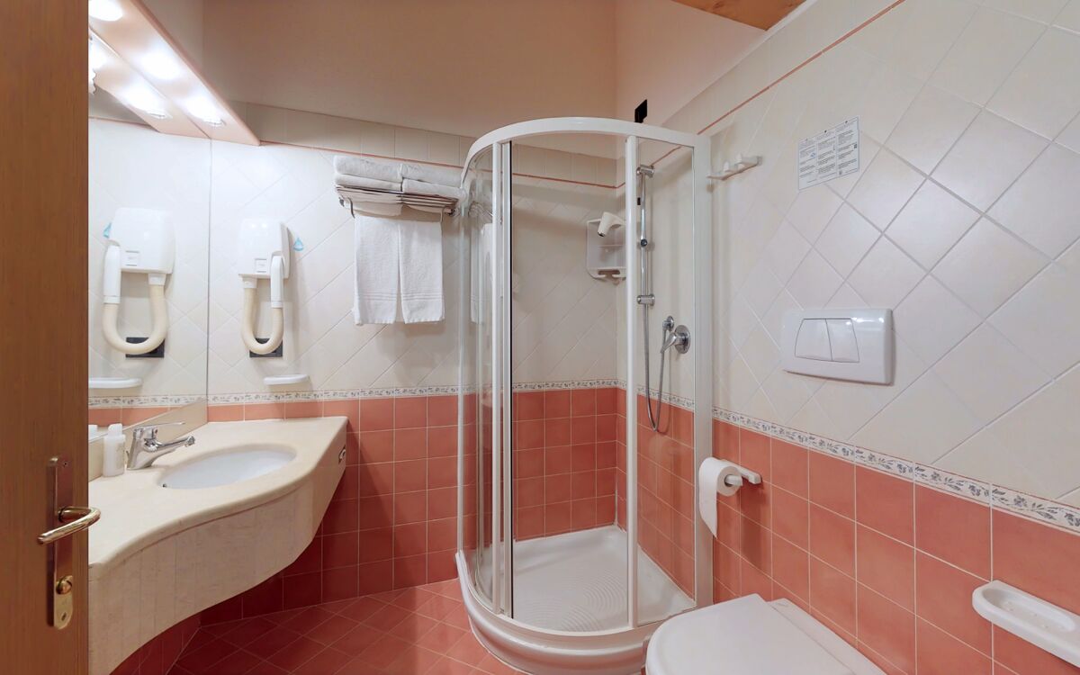 Un baño con lavamanos curvo, cabina de ducha con mampara de vidrio y un inodoro.
